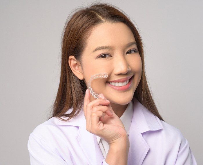 Smiling patient holding clear aligner
