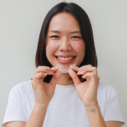 Woman smiling while holding clear aligner