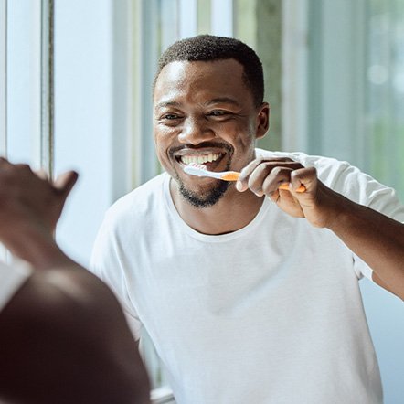Man smiling while brushing his teeth