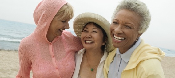 Three senior women laughing on the beach