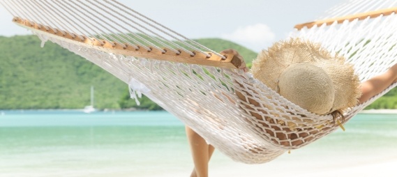 Woman relaxing in hammock with beach in background