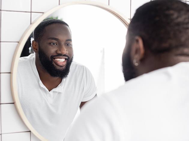 Man in white shirt smiling at reflection in mirror
