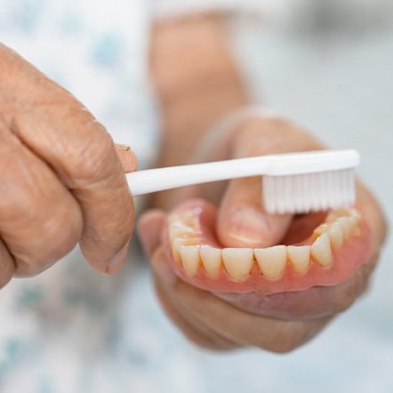 Close up of patient brushing their denture