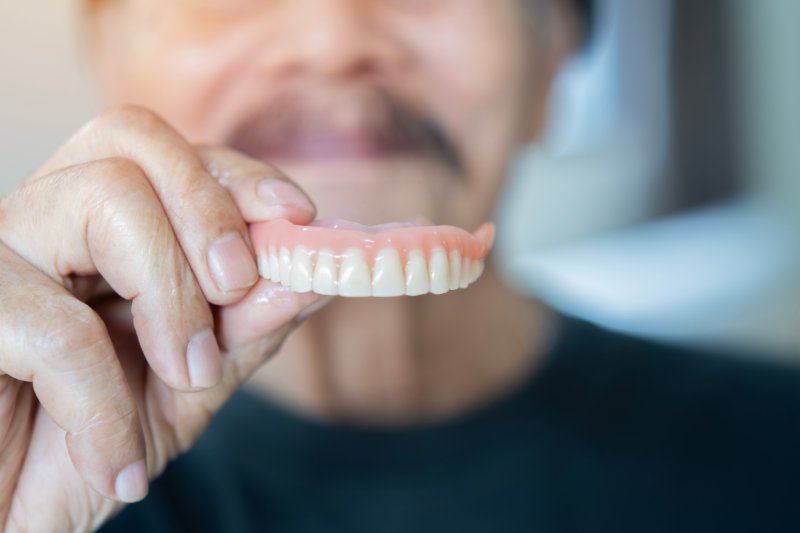 Older patient holding up their whitened dentures